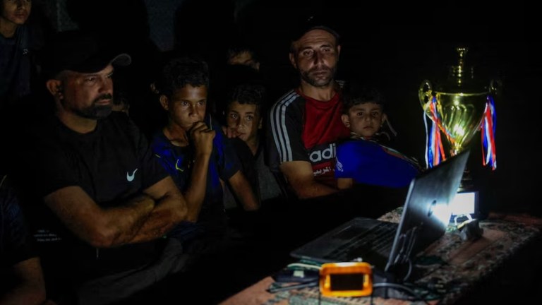 Palestinos assistem a uma partida da Copa do Mundo transmitida em um laptop