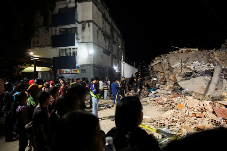 Pessoas se reúnem enquanto equipes de emergência atuam no local de prédio desabado em Caracas após terremotos