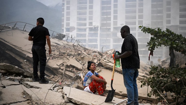 Mulher chora enquanto pessoas procuram por vítimas em meio aos escombros deixados pelos terremotos na Venezuela