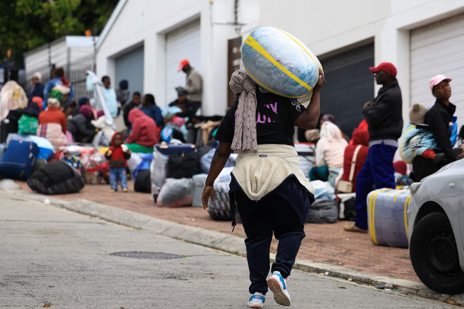 Um migrante zimbabuano carrega bagagem do lado de fora do Consulado do Zimbábue, em meio a temores de violência contra imigrantes, às vésperas do prazo de 30 de junho estabelecido por ativistas que exigem a saída de imigrantes indocumentados do país, na Cidade do Cabo, África do Sul, em 22 de junho de 2026.
