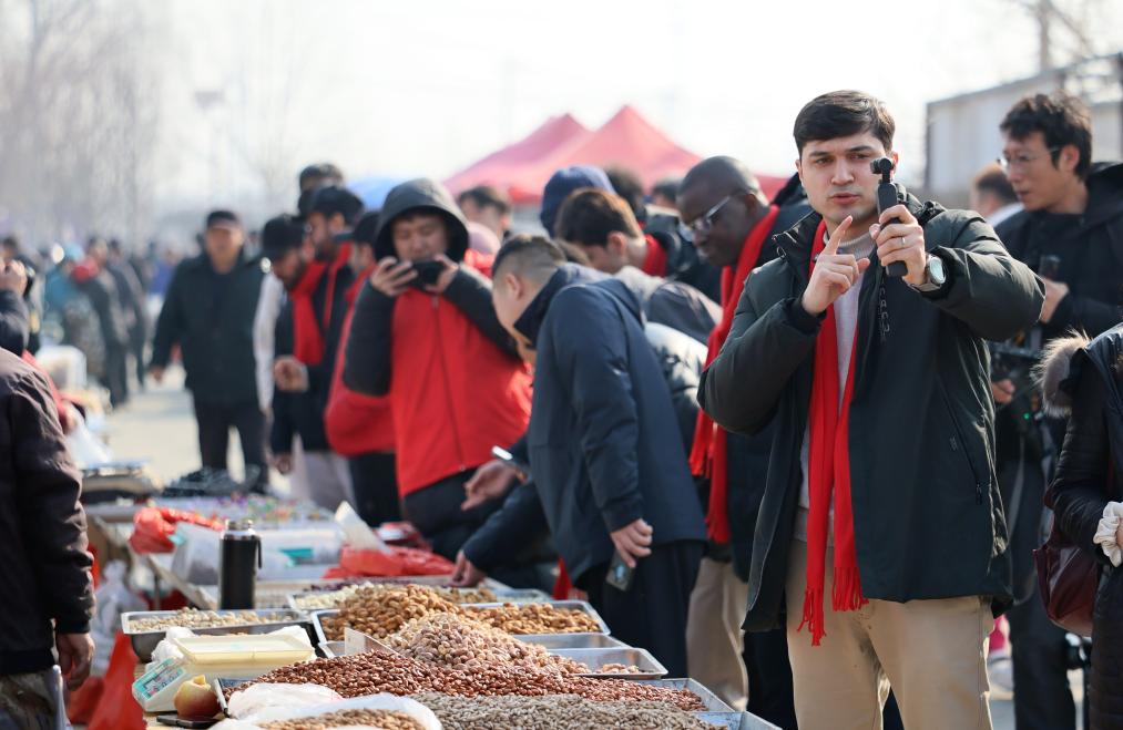 Umar Suleimanov, um estudante tajique de 26 anos da Universidade de Nankai, grava um vlog em uma feira tradicional em Jizhou, Município de Tianjin, norte da China, em 10 de fevereiro de 2026. (Xinhua/Li Ran)