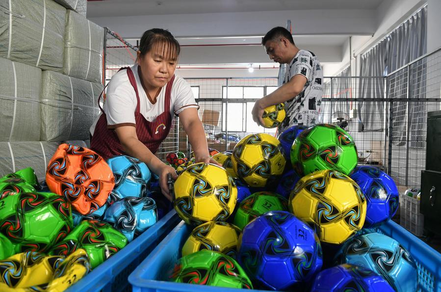 Trabalhadores preparam bolas de futebol para envio em uma empresa local de artigos esportivos em Yiwu, na Província de Zhejiang, leste da China, em 15 de setembro de 2025. (Foto de Shi Kuanbing/Xinhua)